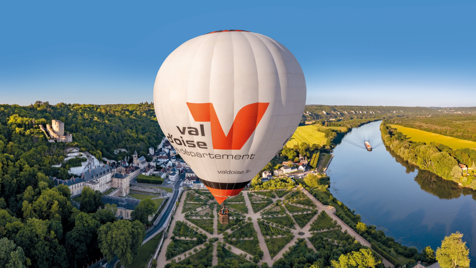 Photo prise en vol de la montgolfière du Vexin logotypé aux couleurs du département du Val d'Oise, au dessus-de La Roche-Guyon